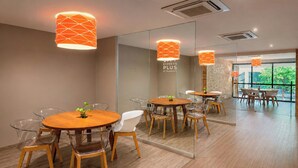 A modern meeting room with round tables, clear chairs, and orange pendant lights. - City Express Plus by Marriott Monterrey Nuevo Sur (Monterrey)