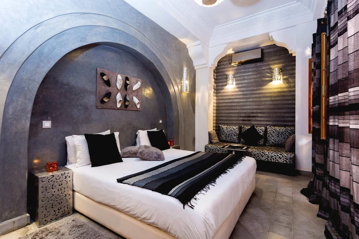 Une chambre moderne dotée d’un grand lit, d’un coin salon et d’un décor mural original.