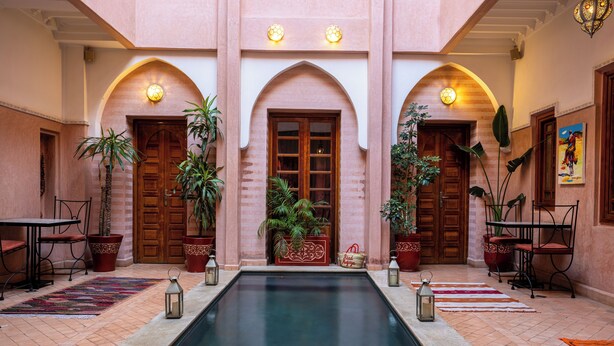 A courtyard with a pool, wooden doors, potted plants, and a tiled floor. - Riad Mazaya (Marrakech)