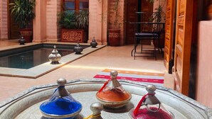 A traditional Moroccan interior with a central fountain, arched doorways, and potted plants. - Riad Mazaya (Marrakech)