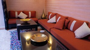 A room with a sofa set, a coffee table with decorative items, and a patterned rug. - Riad Mazaya (Marrakech)