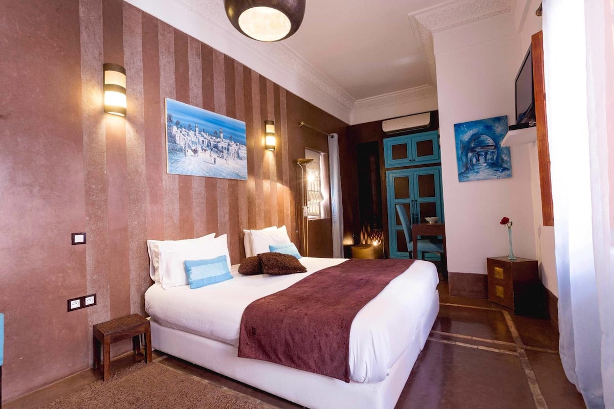 Une chambre d’hôtel avec un grand lit, des murs à rayures et des œuvres d’art.