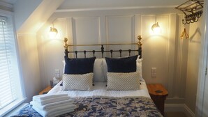 A neatly made bed with a patterned bedspread, two pillows, and a bedside table with a lamp. - South View Guest House (Lynton)