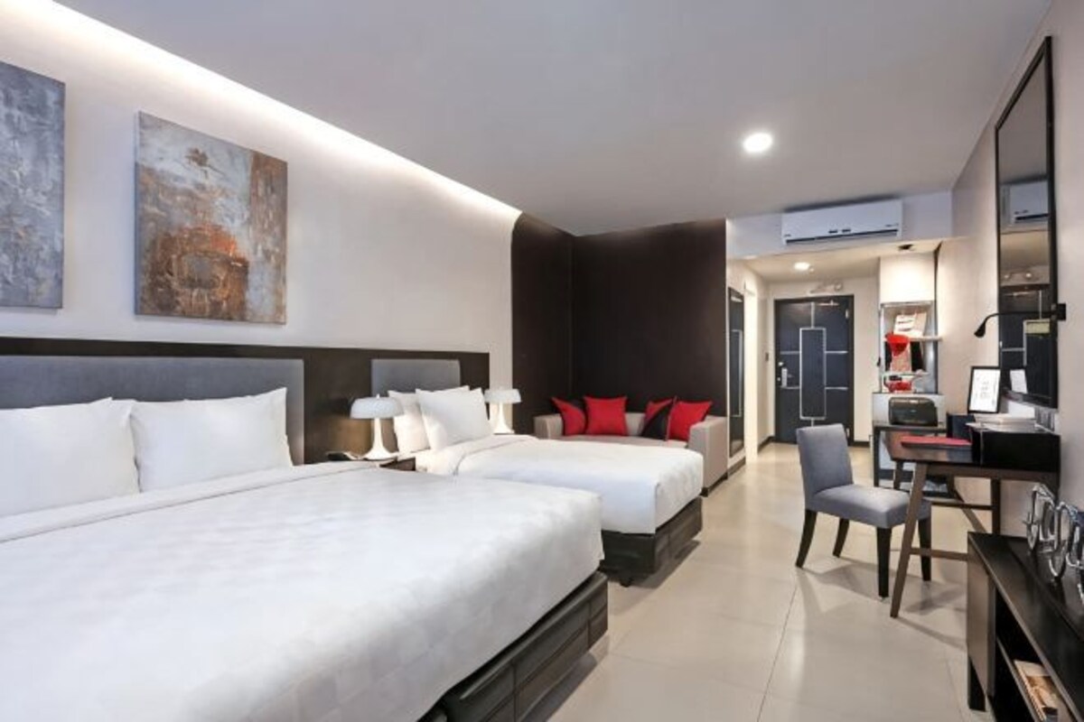 A hotel room with two beds, a desk, and a chair.