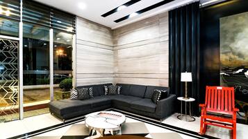 Un salon moderne avec un canapé d’angle, une table basse et un fauteuil rouge.