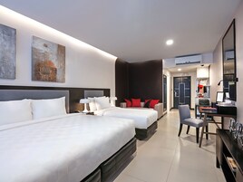 Una habitación de hotel moderna con dos camas, un escritorio, una silla y un espejo grande.