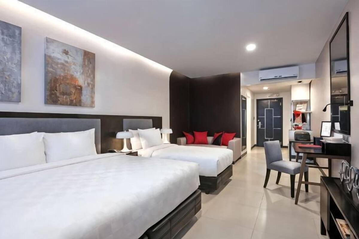 A hotel room with two beds, a desk, and a chair.