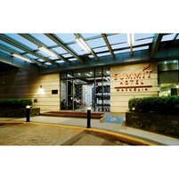Exterior del Summit Hotel, con un diseño moderno, que presenta una entrada de cristal y un cartel.
