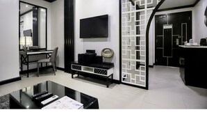 A modern living room with a flat-screen TV, a dining area with a table and chairs, and a kitchen area with a counter and cabinets. - Summit Hotel Magnolia (Quezon City)