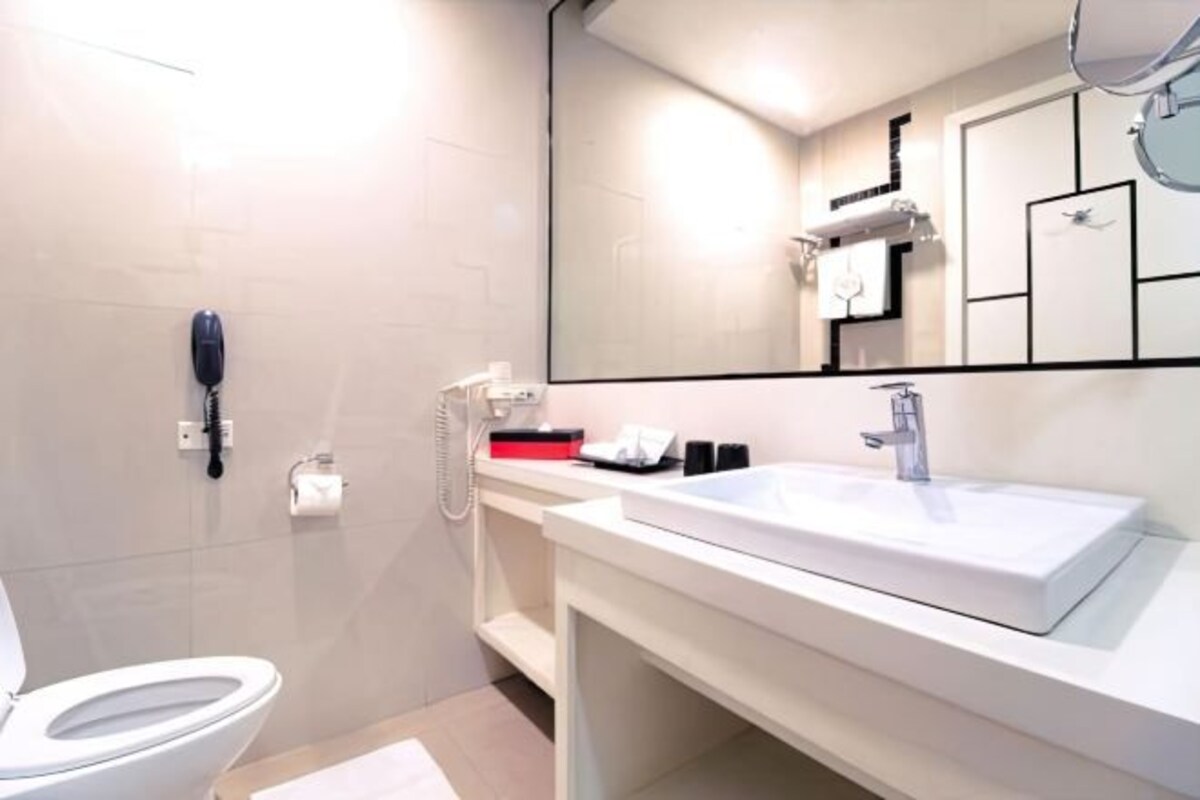 A modern bathroom with a white sink, mirror, and toilet.