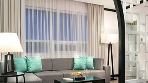 A modern living room with a grey sofa, teal patterned cushions, a glass coffee table, and two floor lamps. - Summit Hotel Magnolia (Quezon City)