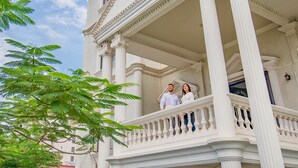 Ein weißes Gebäude mit einem Balkon, der mit aufwendigen Säulen und Geländern verziert ist.