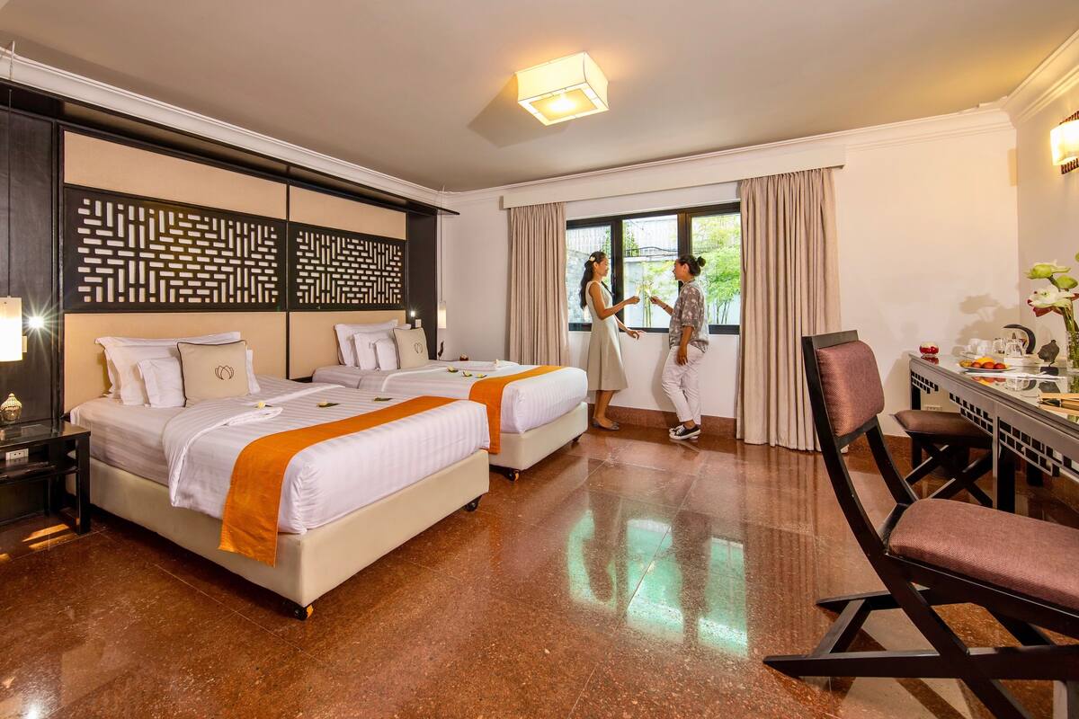A hotel room with two beds, a desk, and a chair.