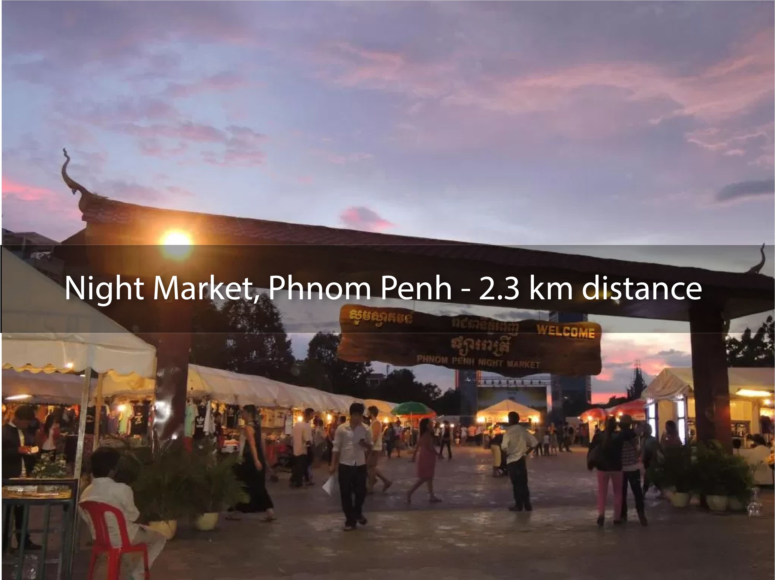 A night market with a welcoming sign and people walking around.