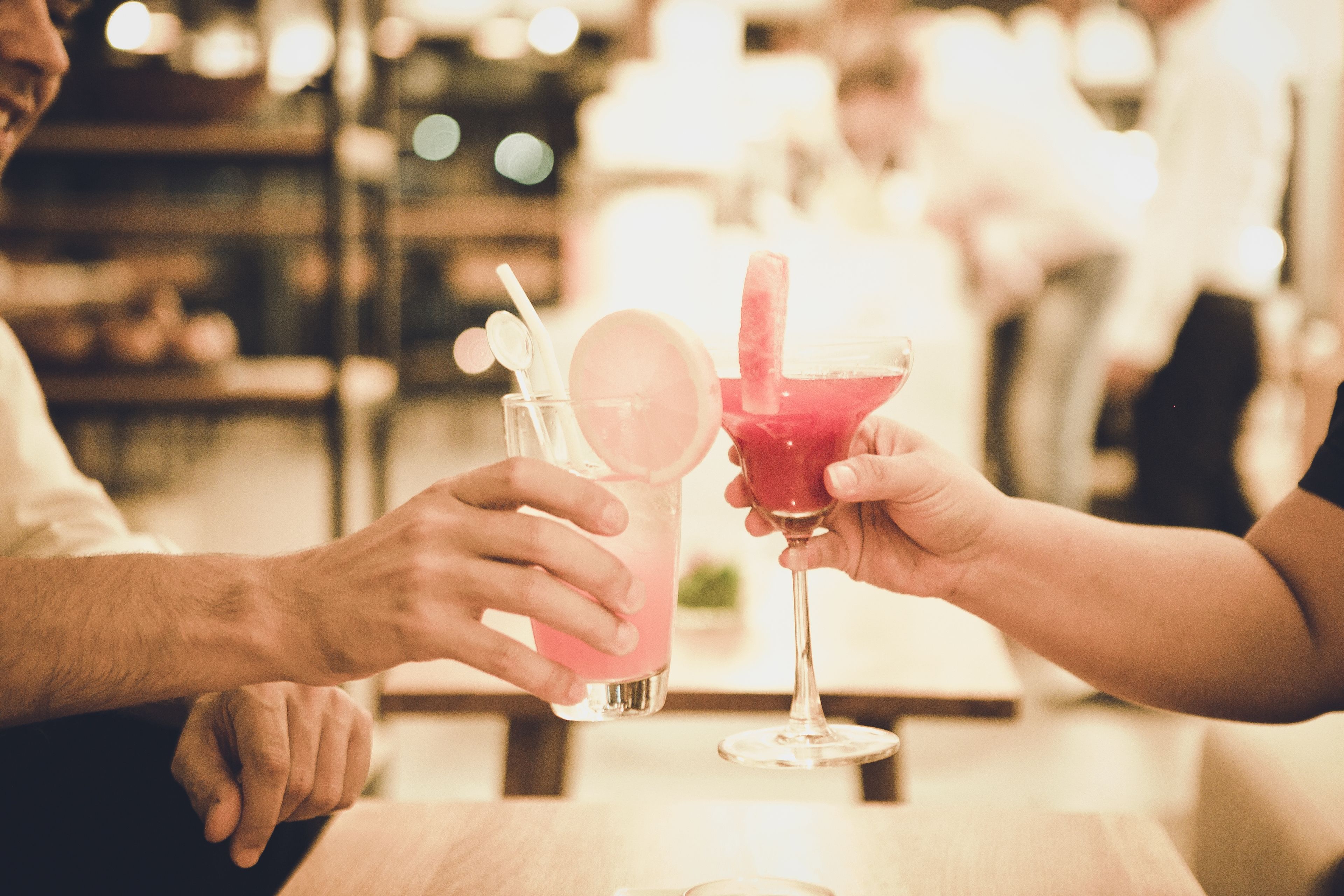 Two people holding drinks at a table in a restaurant.