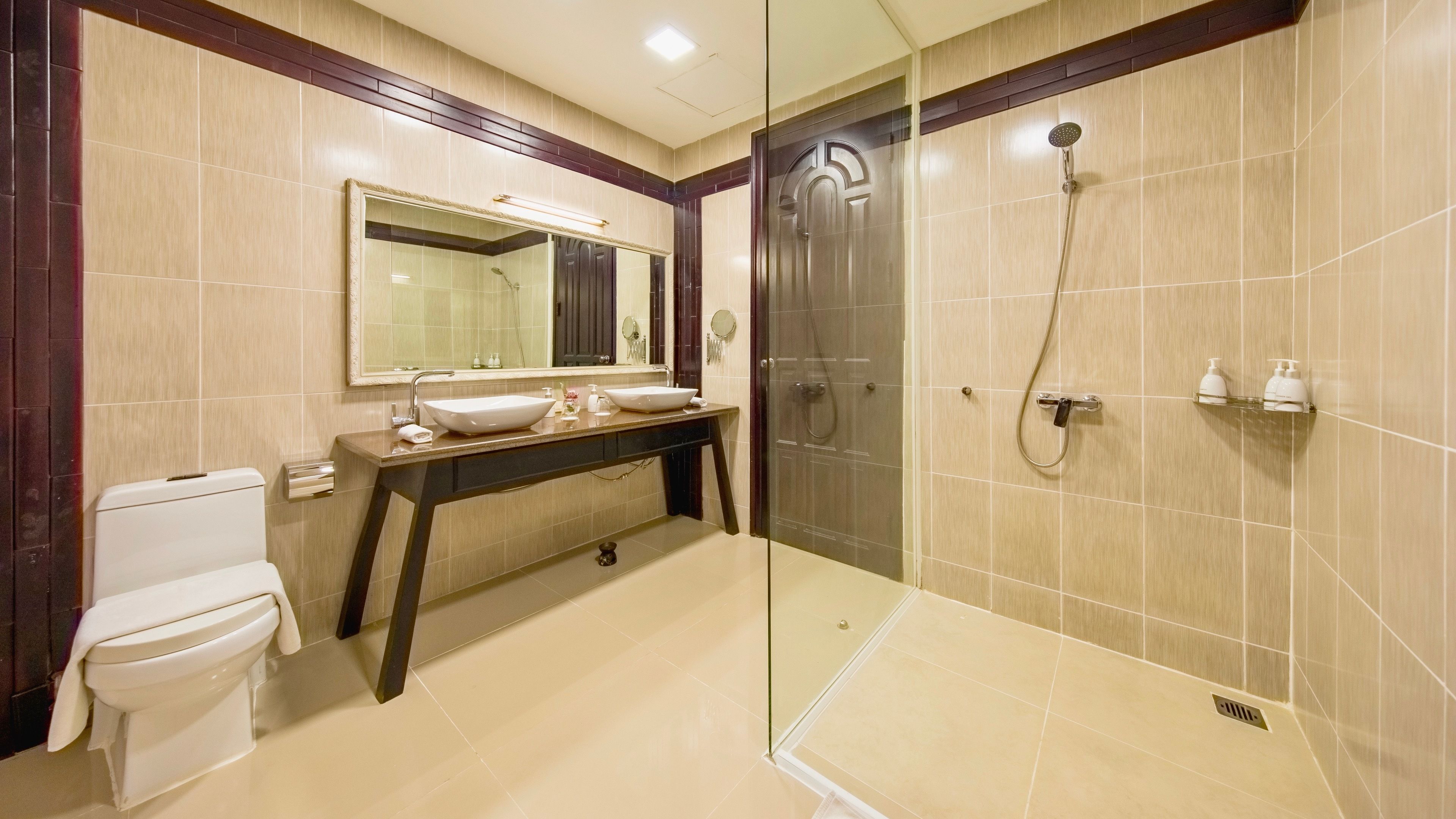 Une salle de bain moderne avec une douche à parois de verre, un meuble-lavabo doté d’un grand miroir et des toilettes.