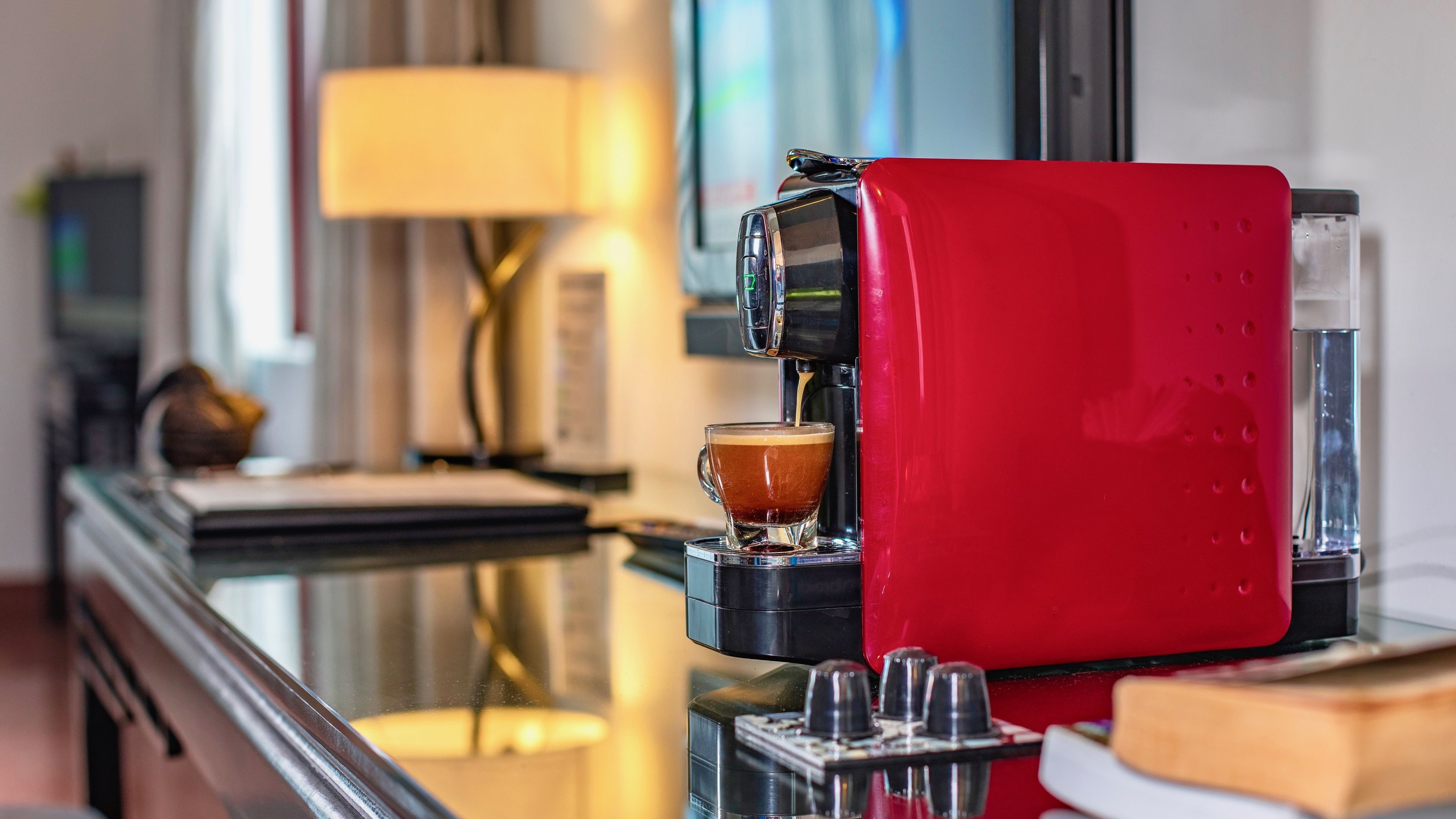 Una cafetera exprés roja preparando una taza de café.