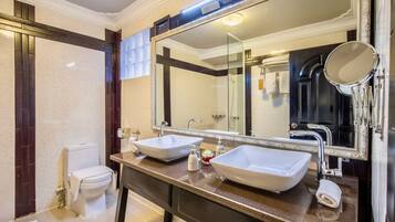 Un baño con dos lavamanos sobre encimera, un inodoro y un espejo grande con marco decorativo.