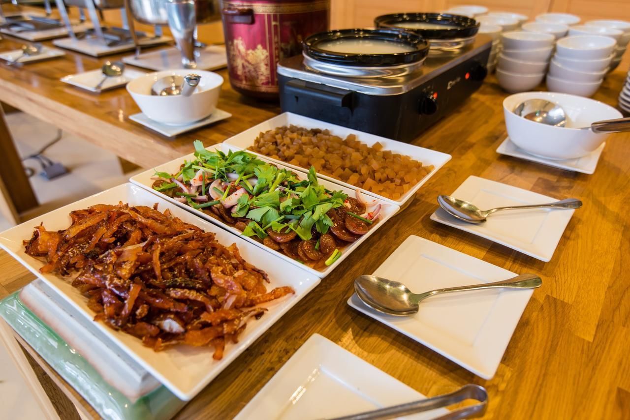 Una mesa de buffet con diversos platos, incluyendo un gran plato de carne salteada, una bandeja de verduras y varios cuencos de sopa.