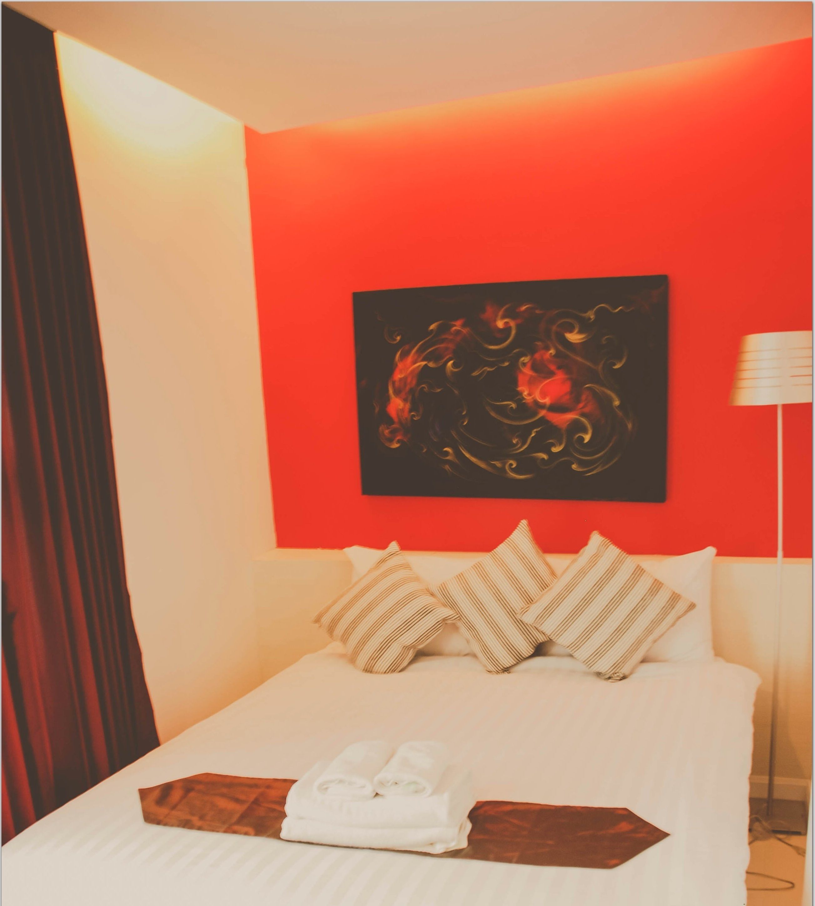 Una habitación de hotel con una cama, almohadas, una manta y un cuadro en la pared.