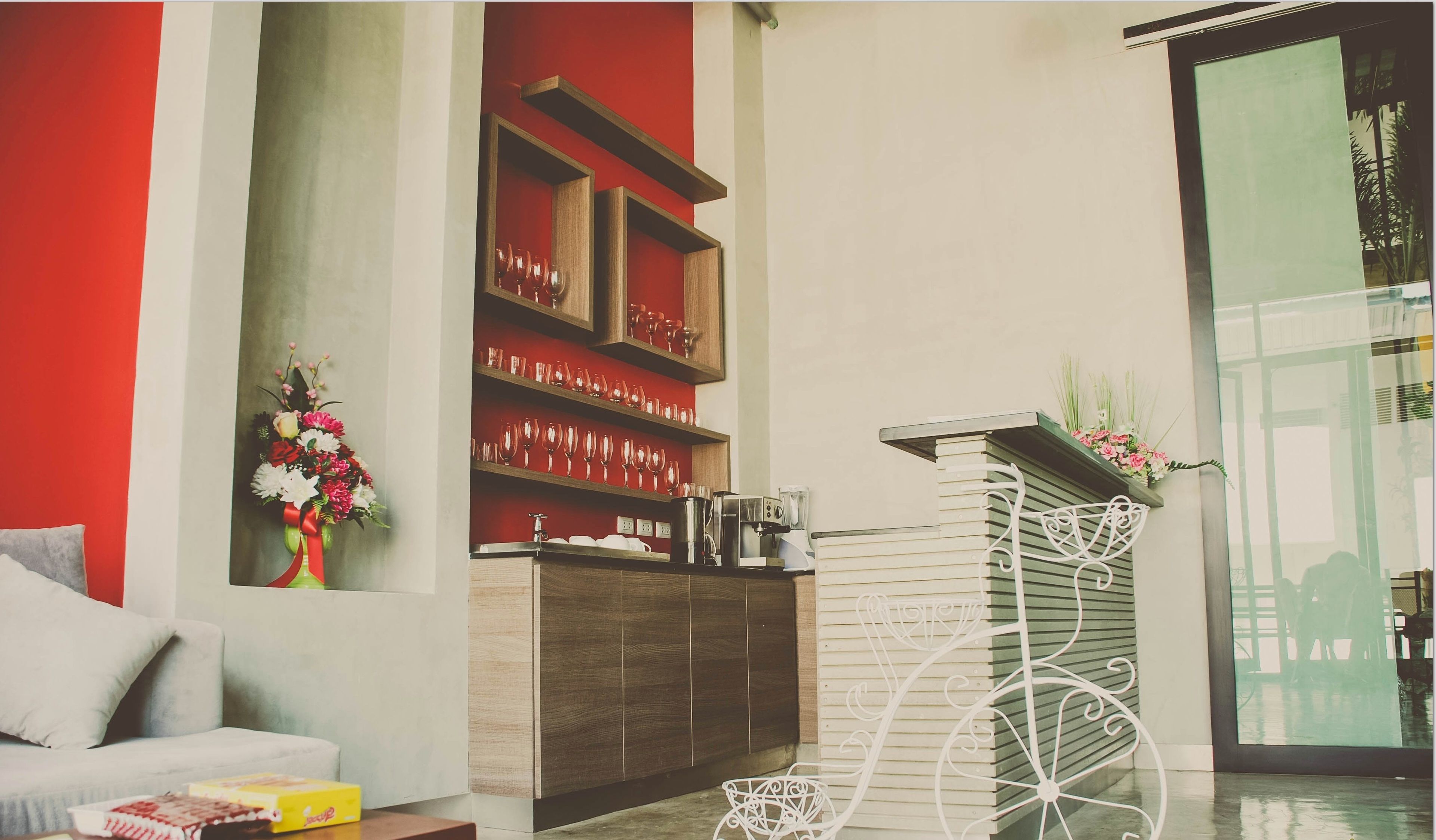 Una sala de estar moderna con un sofá, una mesa de centro, una estantería con objetos decorativos y una silla metálica blanca.