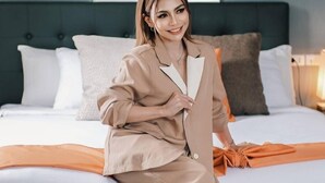 A person sitting on a bed in a room with a dark headboard, white bedding, and a framed picture on the wall. - The Upperhouse Hotel – Boutique Stay with City & River Views (Cagayan de Oro)