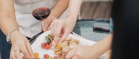 A group of people sitting around a table with a variety of snacks and a glass of red wine.