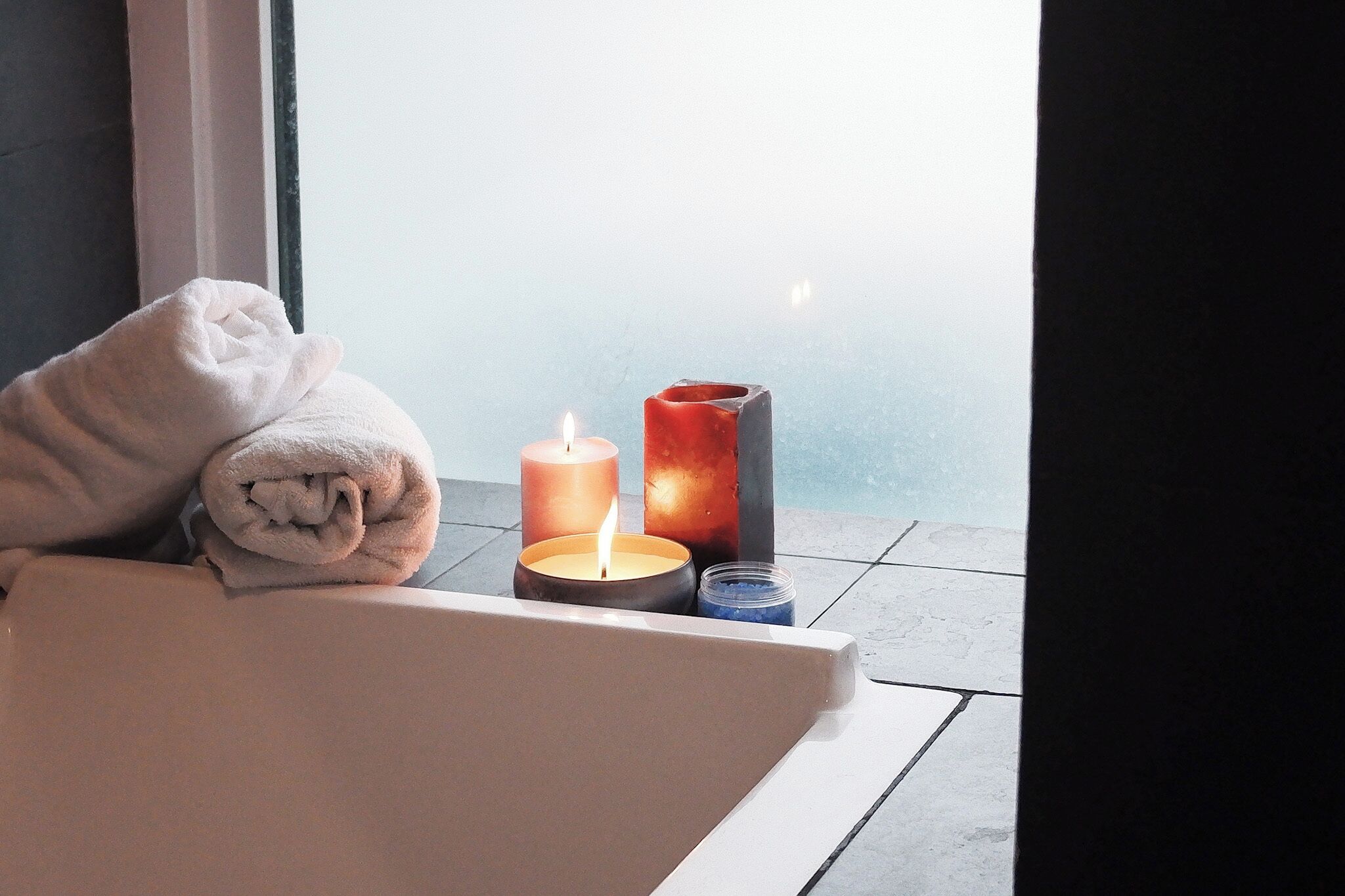 Ein Badezimmer mit einer Badewanne, einem Handtuch und zwei Kerzen.