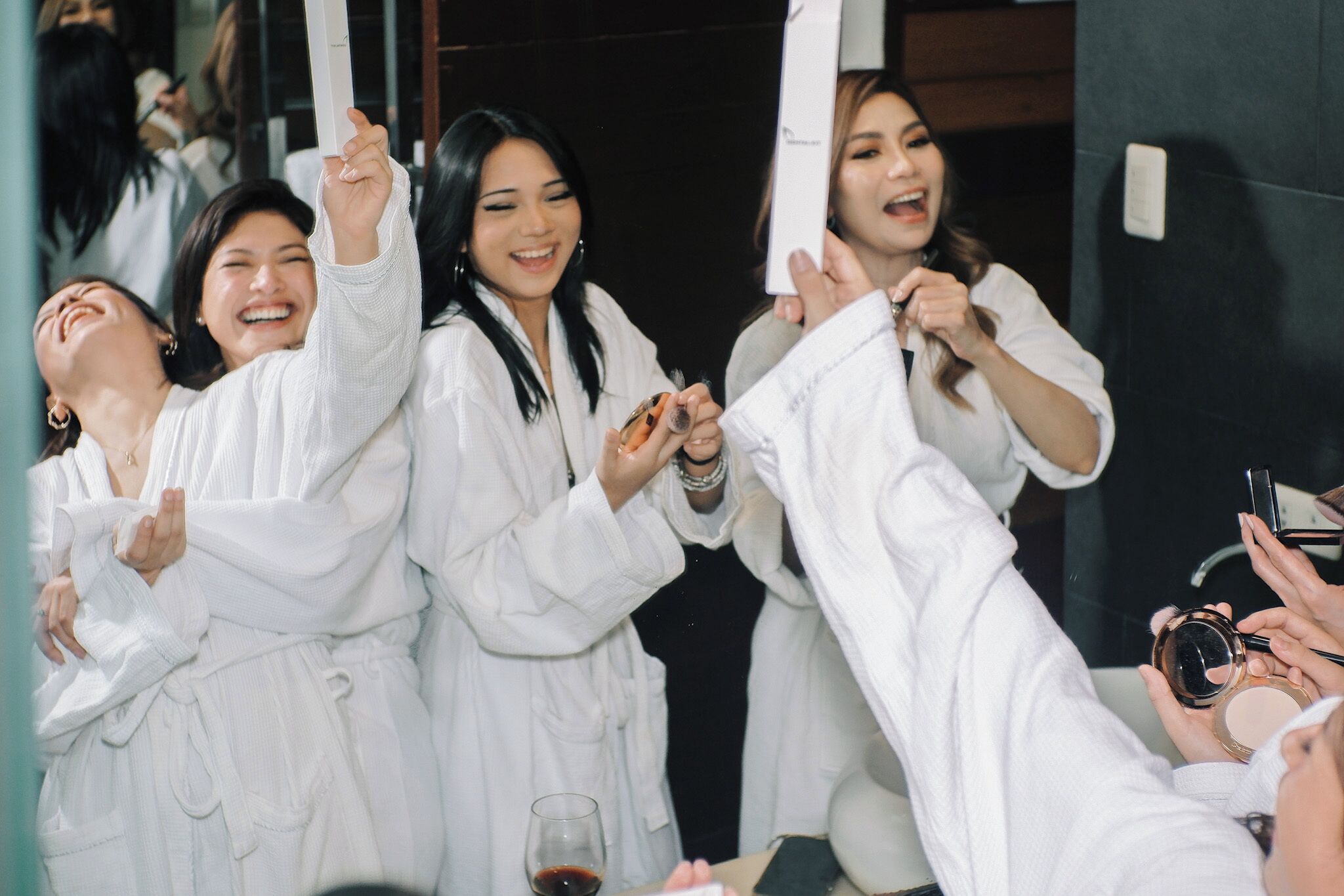 A group of people in white robes, some holding mirrors, in a room with a dark wall and a visible light switch.
