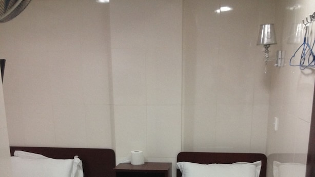 A small, clean room with two single beds, a nightstand with a lamp, and a bathroom with a shower. - China Guest Hostel (Kowloon)