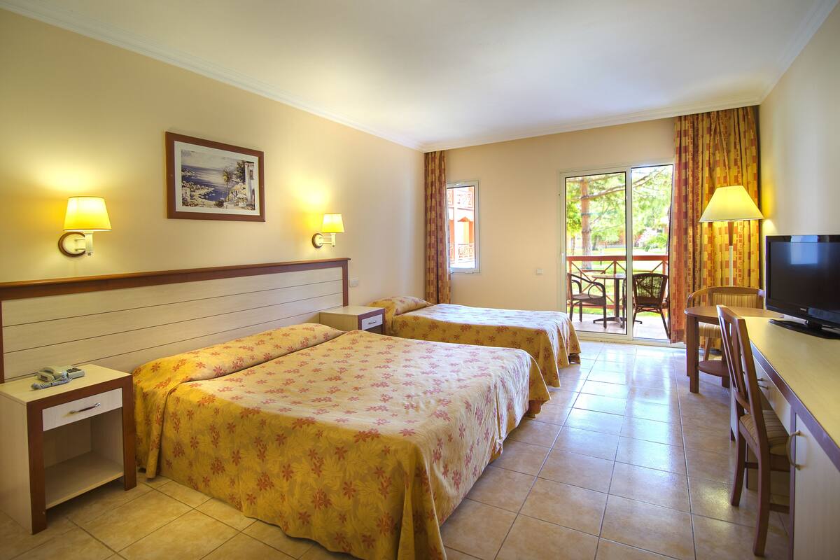 Camera d'albergo con due letti, una televisione, una scrivania e un balcone con vista.