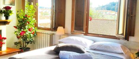 A bedroom with a bed, a tray of breakfast, and a view of the outside.