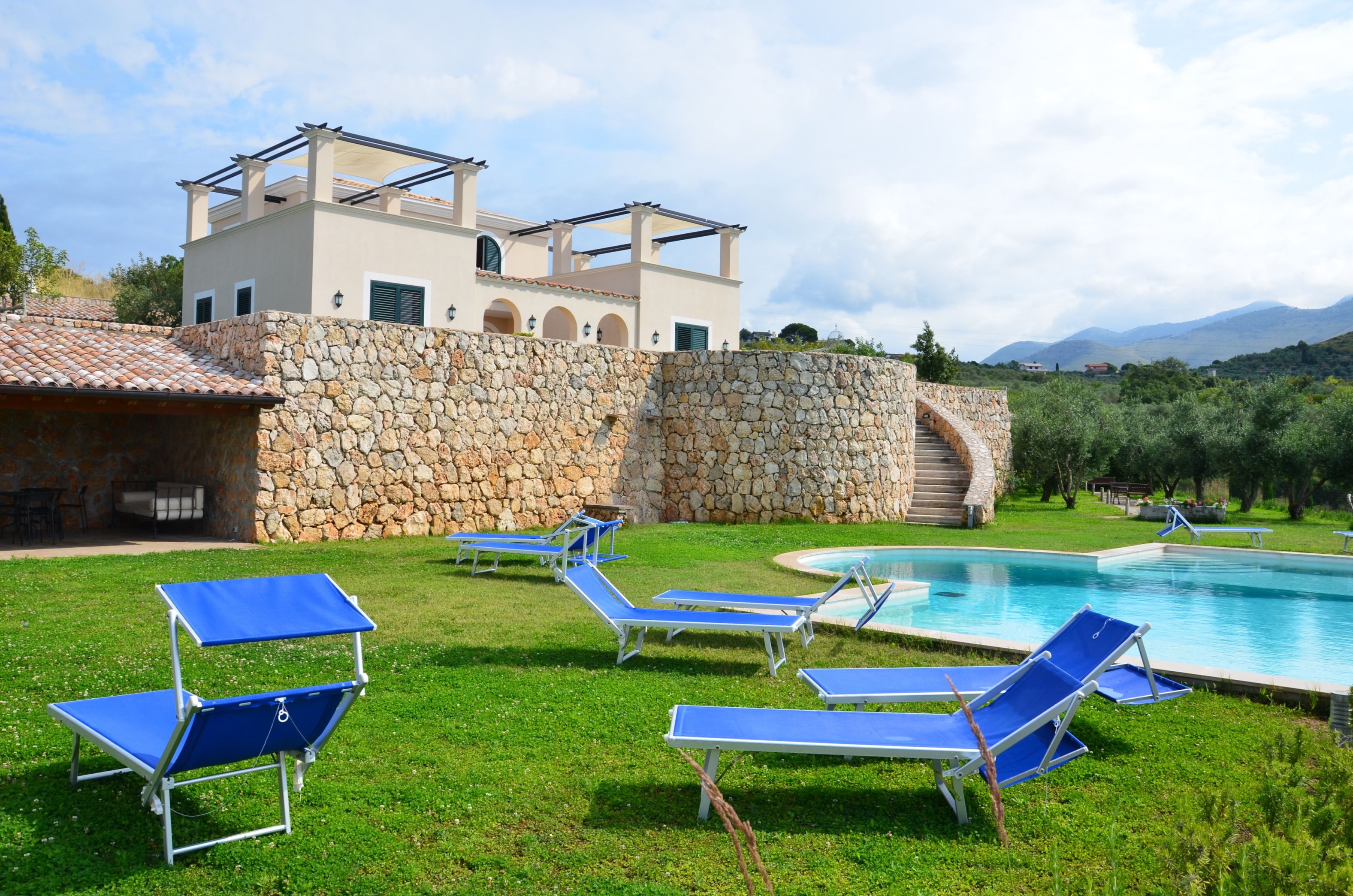 A poolside area with lounge chairs and a stone wall.
