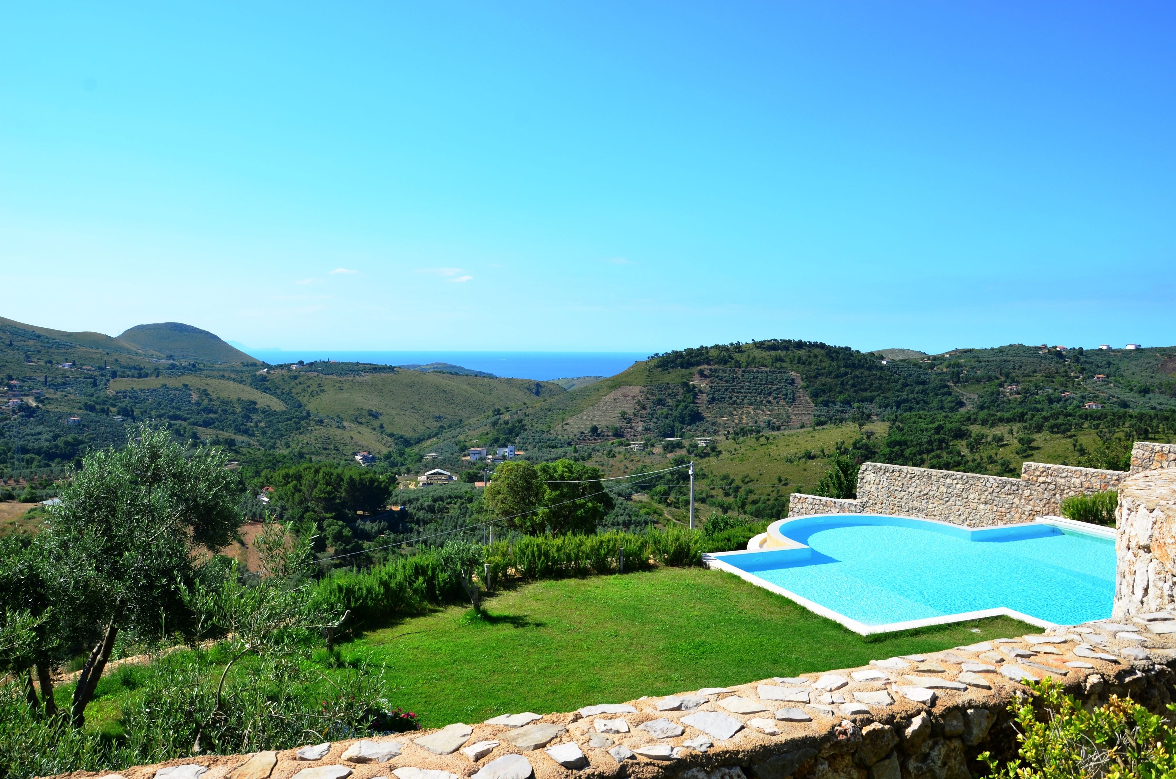 A pool with a stone wall and a view of a valley.