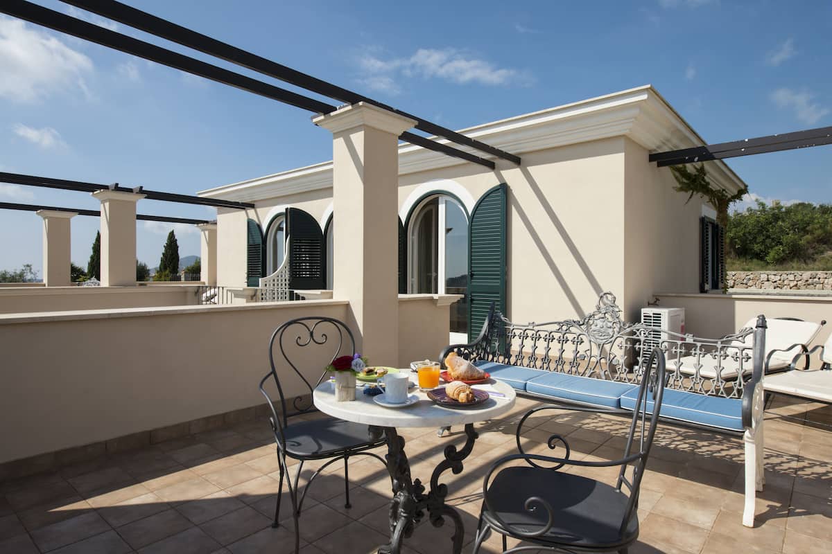 A terrace with a table set for breakfast, outdoor seating, and a view of the surrounding landscape.