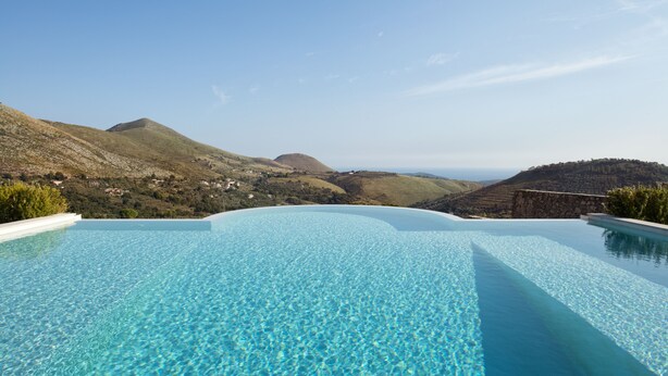 An infinity pool with clear blue water, surrounded by mountainous terrain and a clear sky. - Villa degli Ulivi (Itri)