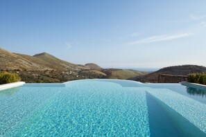 An infinity pool with clear blue water, surrounded by mountainous terrain and a clear sky. - Villa degli Ulivi (Itri)