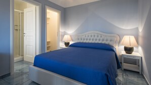 A bedroom with a bed, two bedside tables, a nightstand, and a door leading to a bathroom. - Villa degli Ulivi (Itri)
