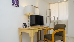 A room with a wooden desk, a television, a lamp, a chair, and a window with a curtain. - Capital O Hotel Dos Mares, Cabo San Lucas (Cabo San Lucas)