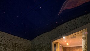 Una habitación con paredes de mosaicos y una ventana que muestra una bañera.