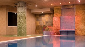 Una piscina con un muro de azulejos y un ventanal grande.