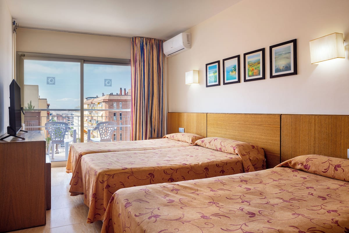 Une chambre d’hôtel avec deux lits, un bureau, une télévision et un balcon donnant sur les bâtiments.