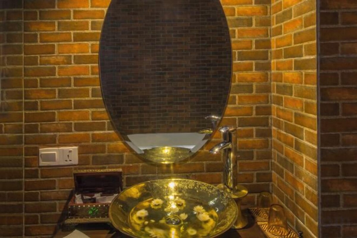 A bathroom with a mirror, a sink, and a decorative brass basin.