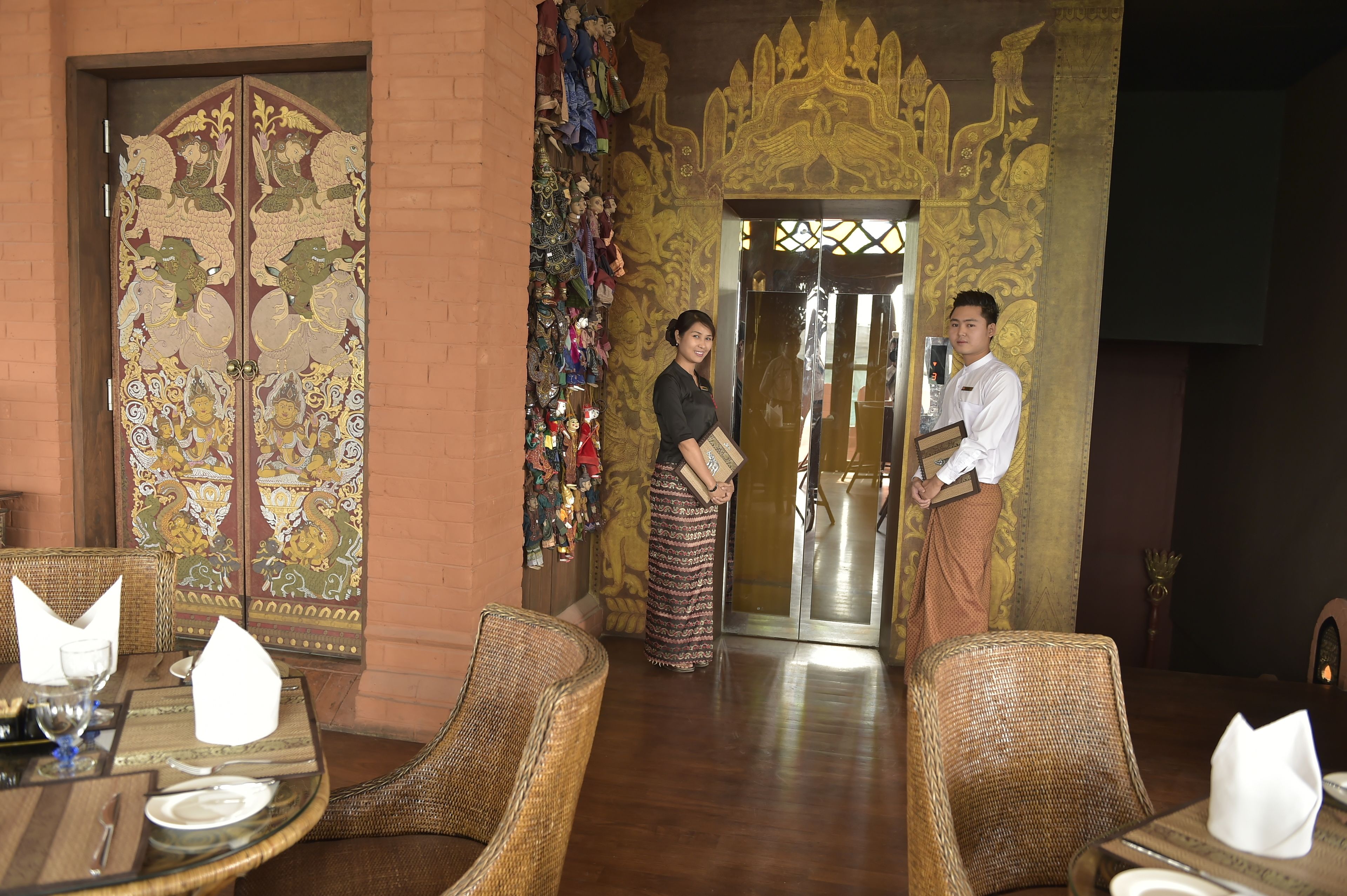 A traditional interior with ornate doors, wicker furniture, and a well-lit dining area.