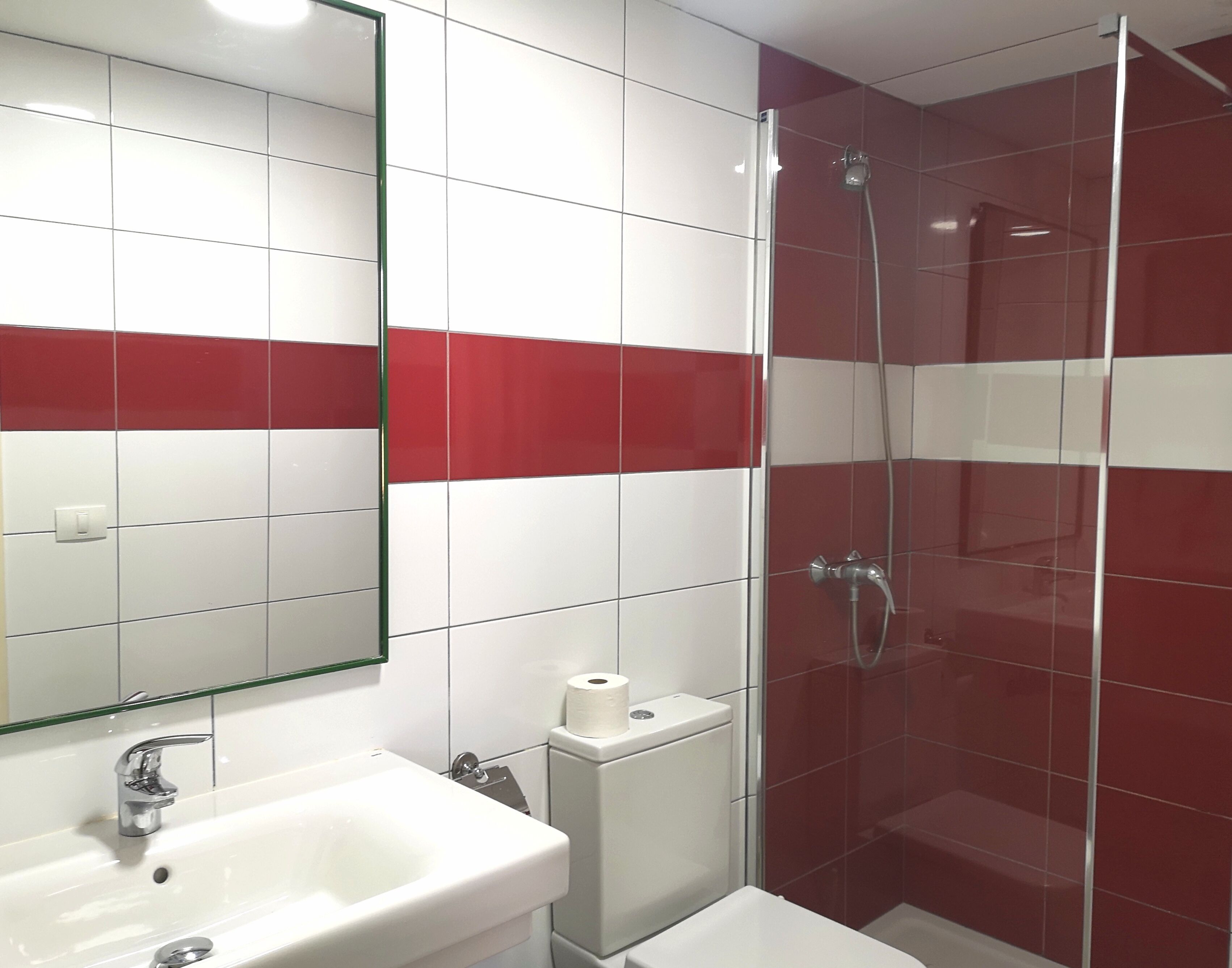 A bathroom with a white sink, a mirror, a toilet, and a shower area.