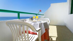 A balcony with a table set for breakfast, overlooking the sea. - Apartamentos Monteparaiso (Mogan)