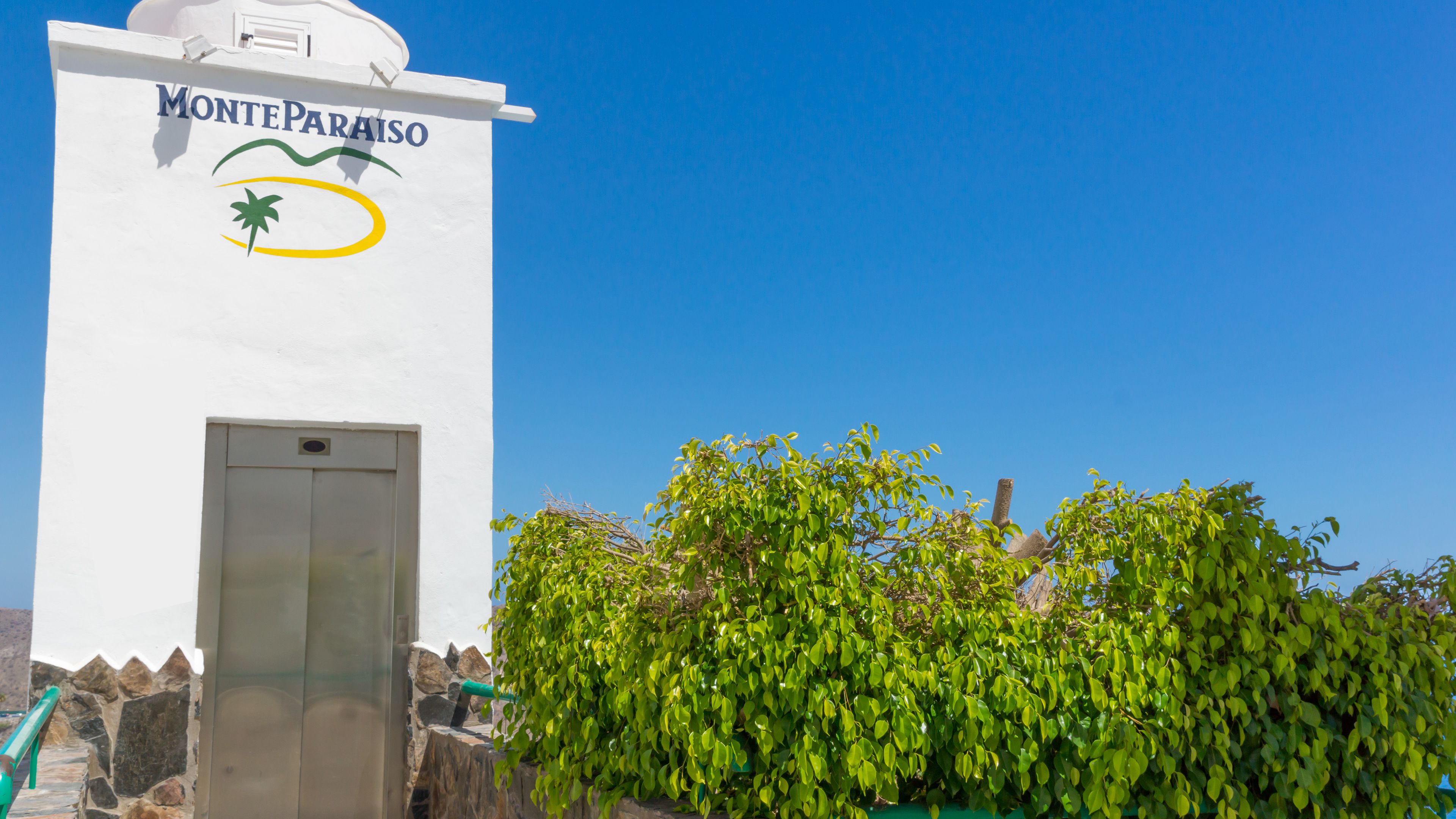 A white building with the sign "Monteparaiso" and a palm tree logo.