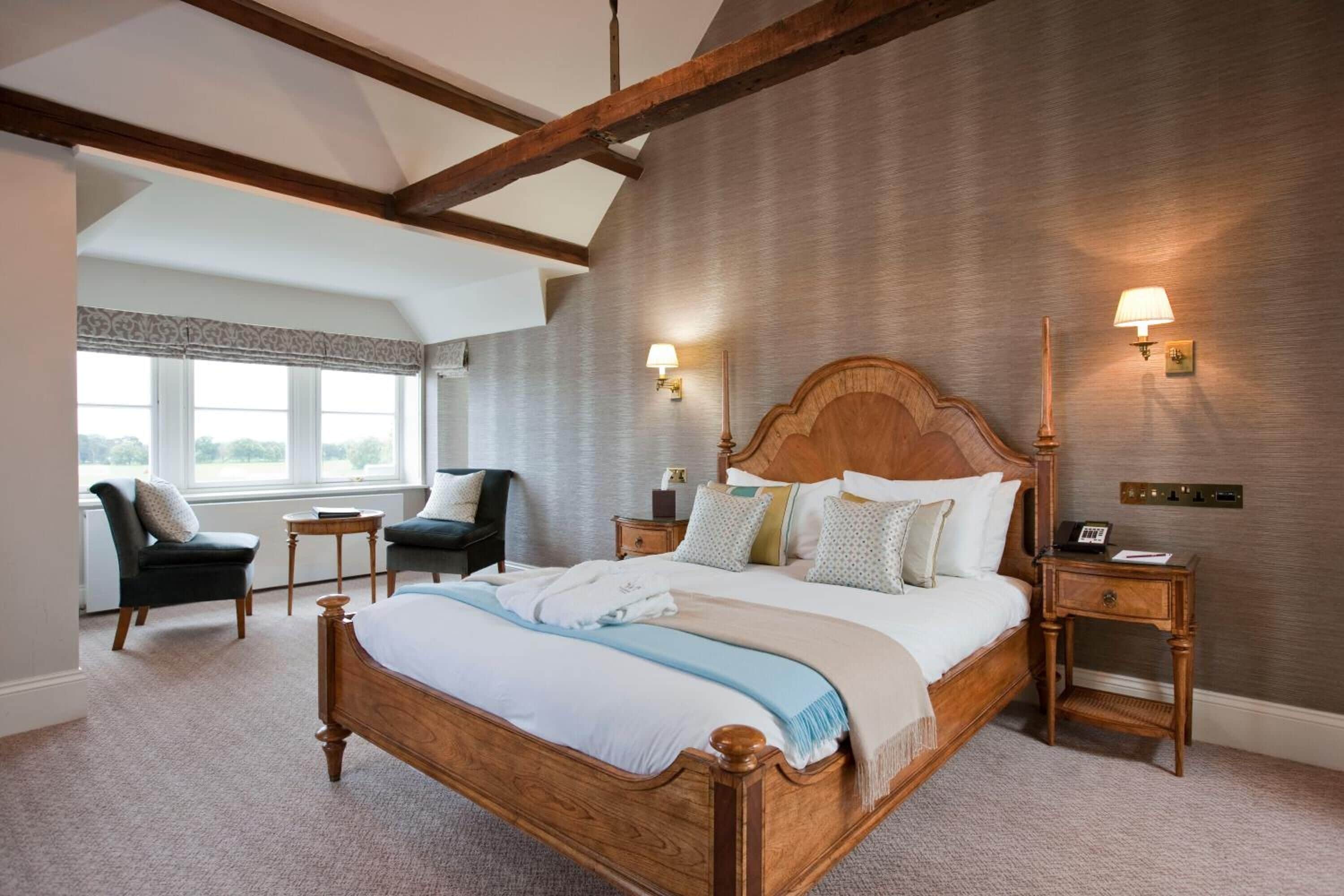 Une chambre à coucher avec un grand lit, deux tables de chevet, une commode, une chaise et une fenêtre avec des rideaux.