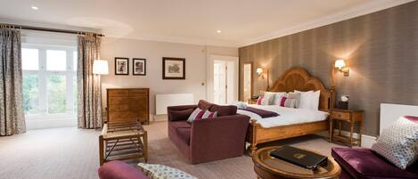 A well-lit bedroom with a large bed, a sofa, a small table, and a wooden cabinet.