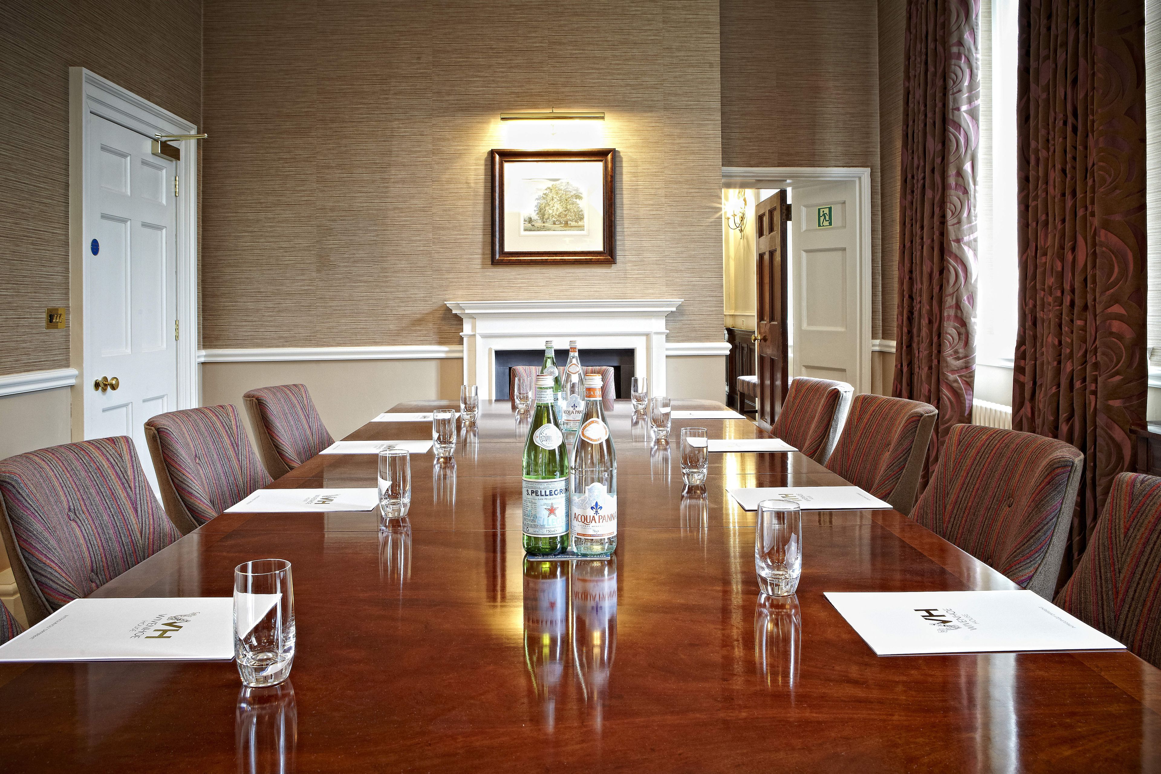 A conference room with a long table, chairs, and a fireplace.